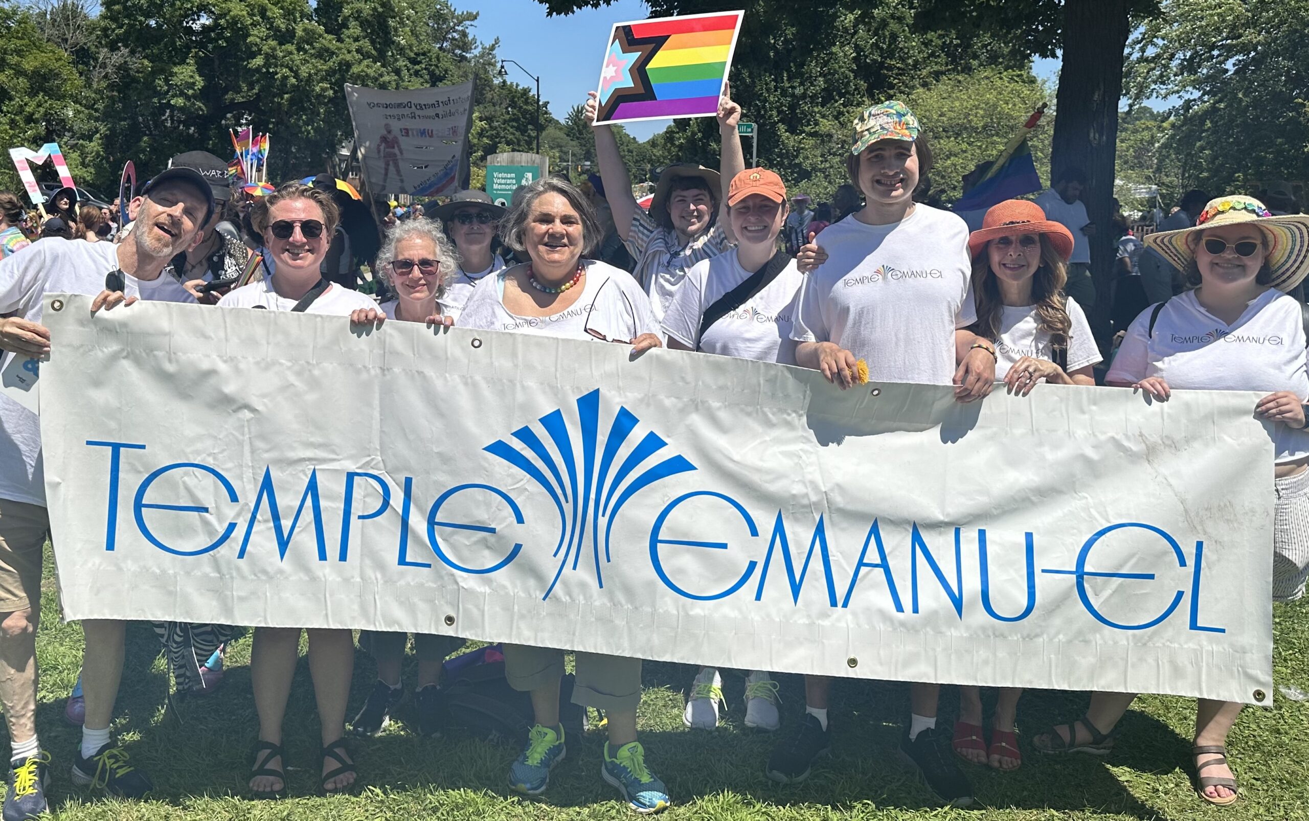 Temple Emanu-El members holding up our logo at the 2024 Pride Parade