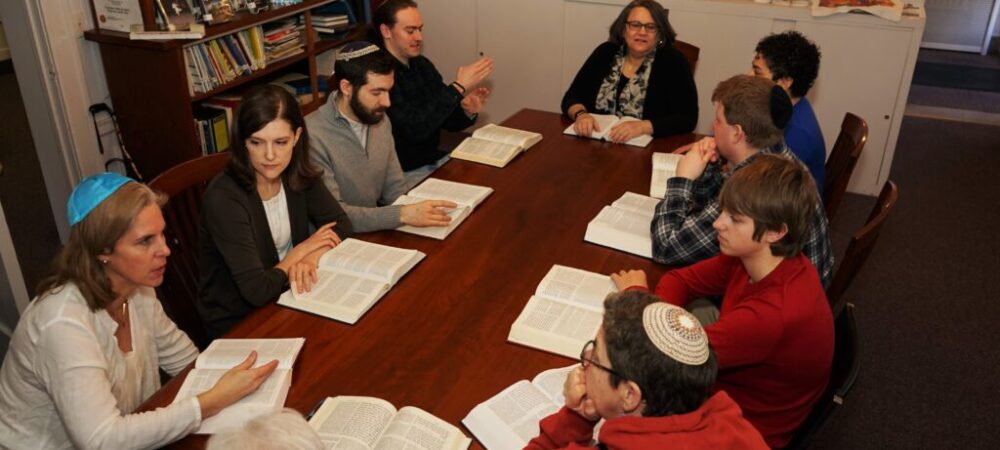 People around large table discussing Torah